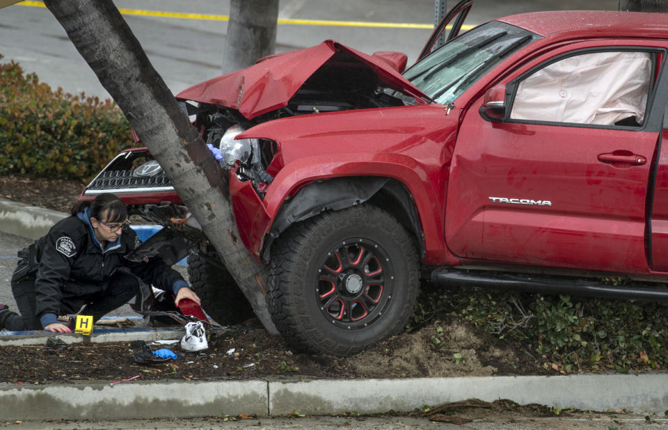 Heather Barclay, bottom left, an accident investigator with the Fullerton Police Department, gathers evidence from an early-morning accident involving a suspected DUI driver on Sunday, Feb. 10, 2019, in Fullerton, Calif. Authorities say a suspected drunken driver was arrested after his pickup truck plowed into a crowd on a sidewalk, injuring multiple people, including some victims who were trapped under the vehicle. (Mindy Schauer/The Orange County Register via AP)