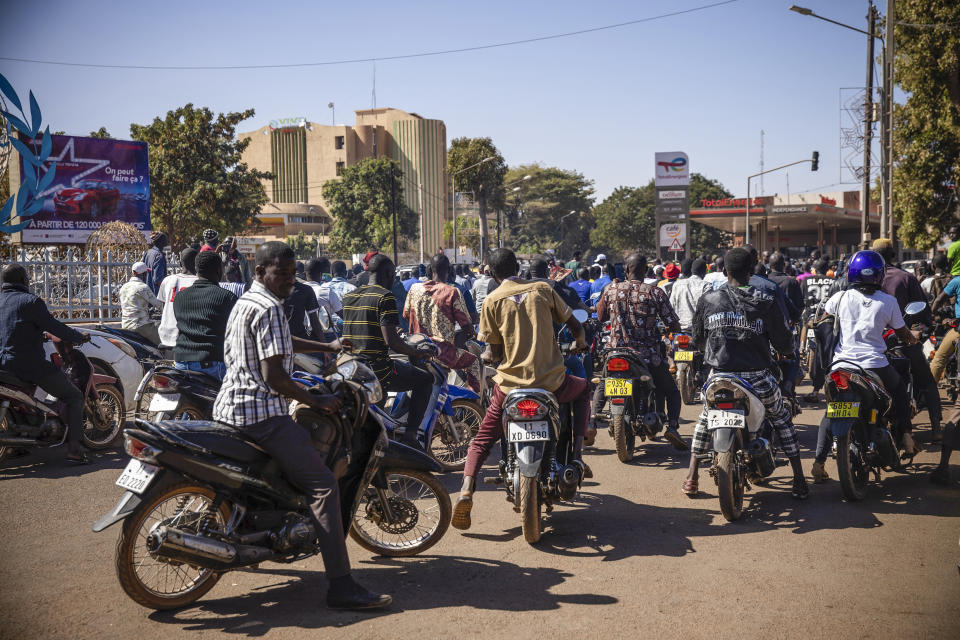 People cheer in support of putschist soldiers near the national television station in Ouagadougou, Monday, Jan. 24, 2022. Two mutinous soldiers told The Associated Press that Burkina Faso’s President Roch Marc Christian Kabore is being held by the rebellious soldiers. Gunshots rang late Sunday night near the president’s residence and in the early hours of Monday a battle took place at the presidential palace while a helicopter flew overhead. (AP Photo/Sophie Garcia)