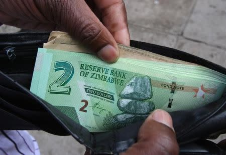 A Zimbabwean man shows off a new bond note outside a bank in the capital Harare,Zimbabwe November 28,2016.REUTERS/Philimon Bulawayo