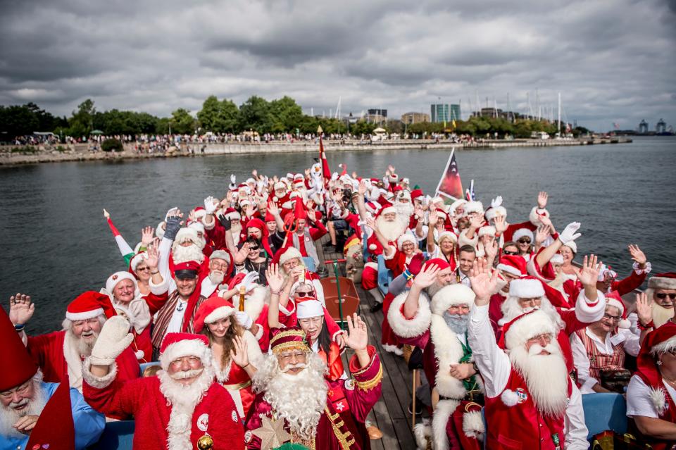 <p>People dressed as Santa Claus wave as they take part in a canal tour that is part of the annual World Santa Claus congress on July 23, 2018 in Copenhagen. (Photo: Mads Claus Rasmussen/Ritzau Scanpix/AFP/Getty Images) </p>