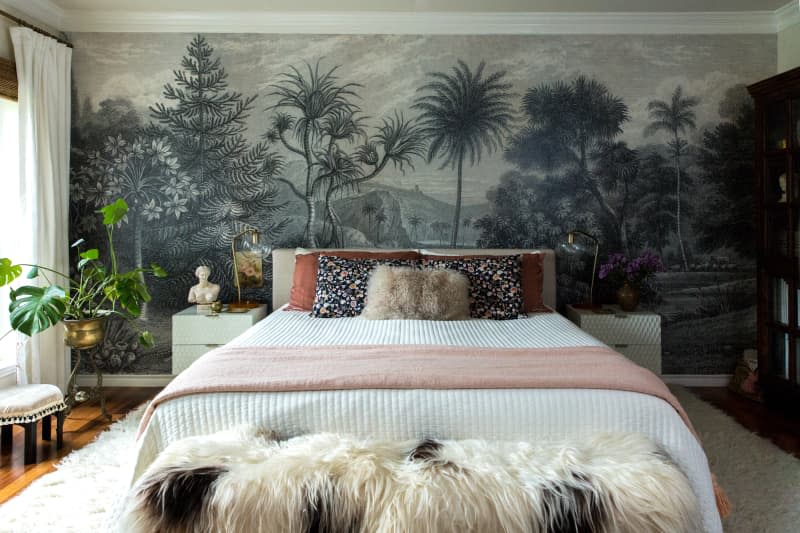 A bed in front of a wall with a mural of trees