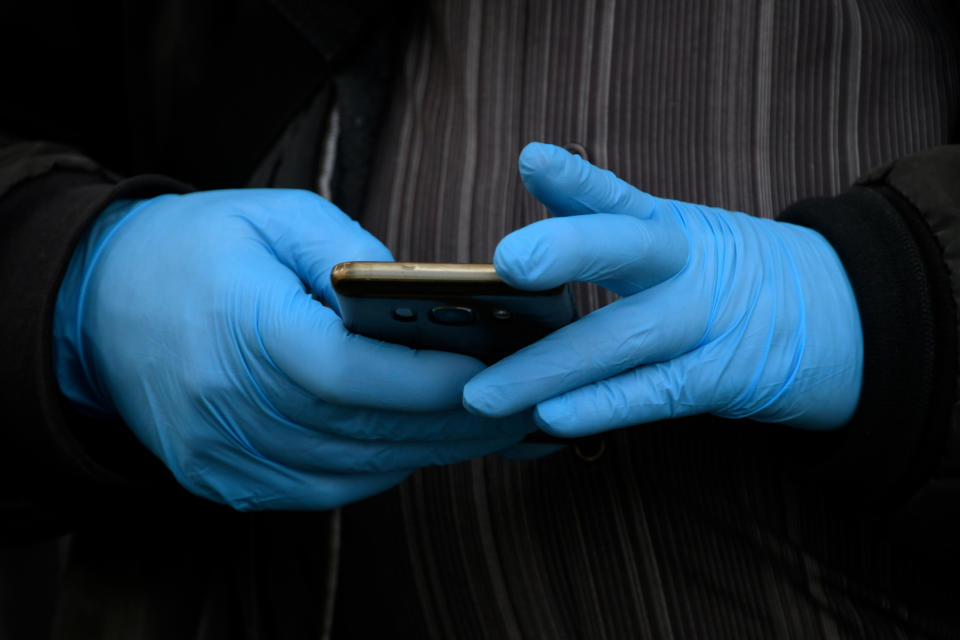 A man wearing gloves as a protective measure, holds a smartphone in Madrid on March 19, 2020. - Spain today announced that deaths from the novel coronavirus had jumped by nearly 30 percent over the past 24 hours to 767. The number of people who have contracted the disease has meanwhile grown by around 25 percent to 17,147, according to health ministry figures, bringing Spain's tally near that of Iran, the world's third most affected country after China and Italy. (Photo by Gabriel BOUYS / AFP) (Photo by GABRIEL BOUYS/AFP via Getty Images)