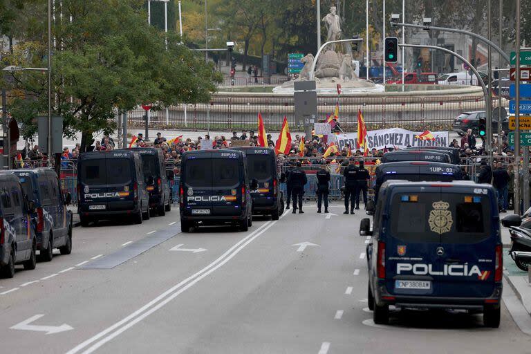 Los policías se encuentran junto a un vehículo policial frente a manifestantes reunidos durante un debate parlamentario en vísperas de una votación para elegir al próximo primer ministro de España, en Madrid el 15 de noviembre de 2023.