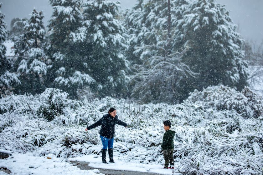 Rancho Cucamonga, CA - February 25: Valeria Roman, 23, left, and her 5-year-old-son Emiliano India Roman play in freshly fallen snow on top of Haven Avenue on Saturday, Feb. 25, 2023 in Rancho Cucamonga, CA. (Irfan Khan / Los Angeles Times)