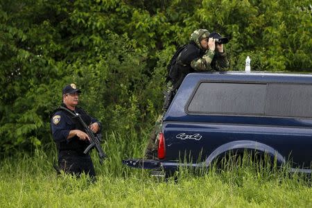 Law enforcement officers look out over a field near Willsboro, New York June 9, 2015. REUTERS/Chris Wattie