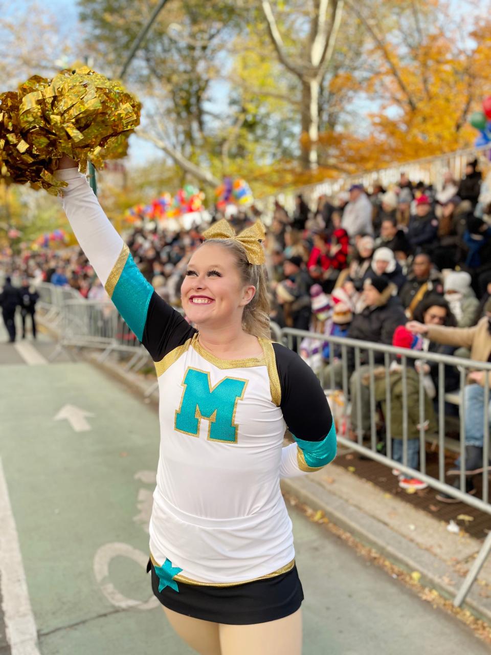 Washington High School cheerleader Becca Madden waves to spectators along the route at the Macy’s Thanksgiving Day parade.