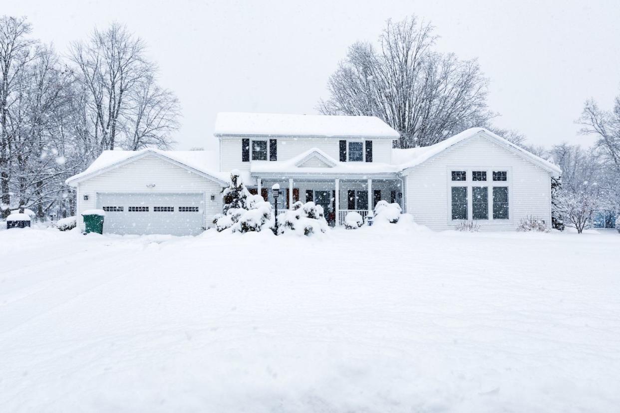 suburban colonial home during extreme blizzard snow storm