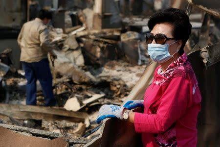 Alex Ham, left, and his mother Lilly Ham search for a safe in Lilly's home that was destroyed in wildfire that tore through Santa Rosa. REUTERS/Jim Urquhart