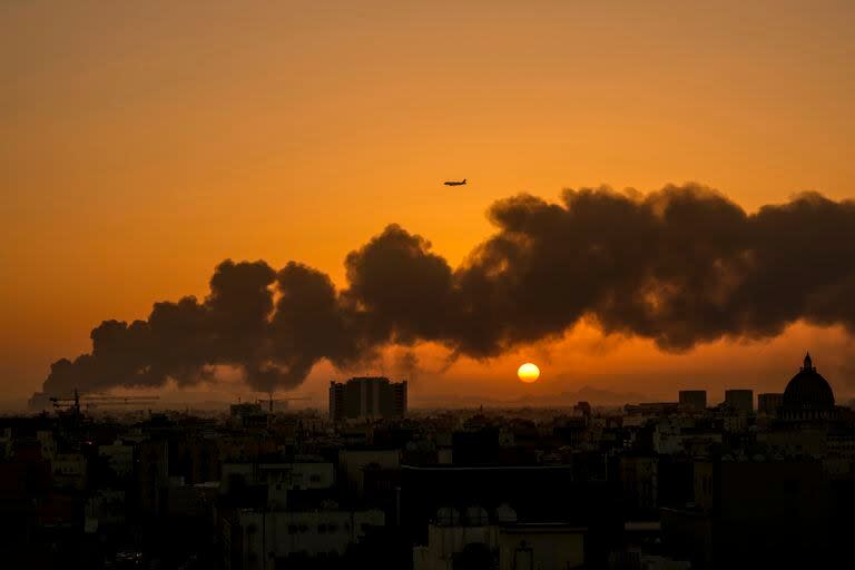 Un avión de pasajeros sobrevuela un incendio en un depósito de combustible de Saudi Aramco luego de un ataque de los rebeldes hutíes yemeníes, antes de una carrera de Fórmula Uno, en Yeda, Arabia Saudí, el 26 de marzo de 2022. La F1 dijo que la carrera se realizará el domingo 27 de marzo de 2022 como estaba planeado.(AP Foto/Hassan Ammar)