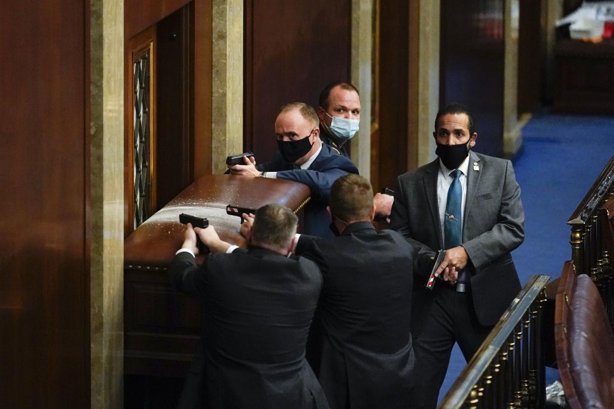 U.S. Capitol Police with guns drawn stand near a barricaded door as protesters try to break into the House Chamber at the U.S. Capitol on Wednesday, Jan. 6, 2021, in Washington.