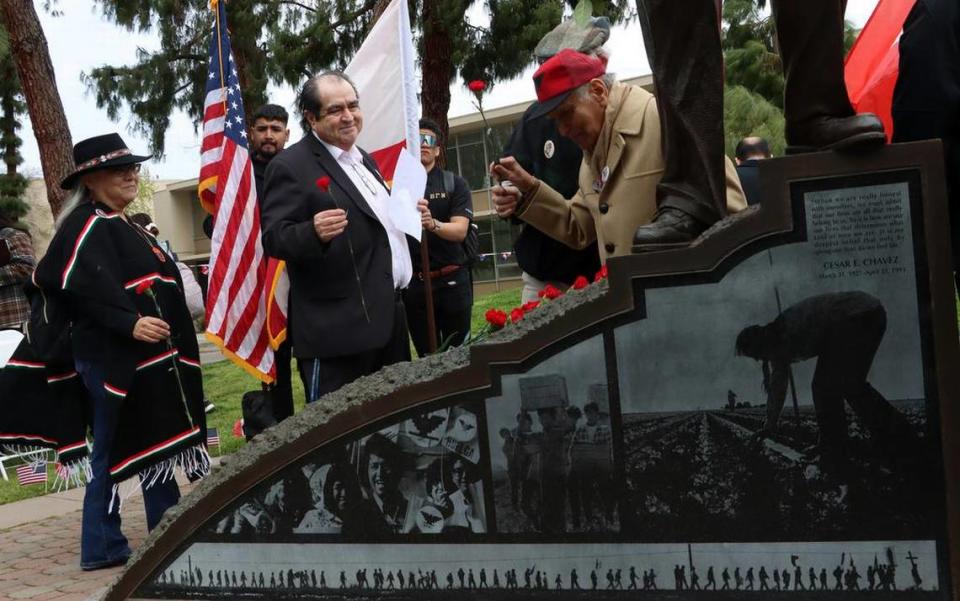 Dr. Sudarshan Kapoor helps place red carnations at the base of a bronze statute of farmworker leader César E. Chávez during March 22, 2023 celebration at Fresno State’s Peace Garden.