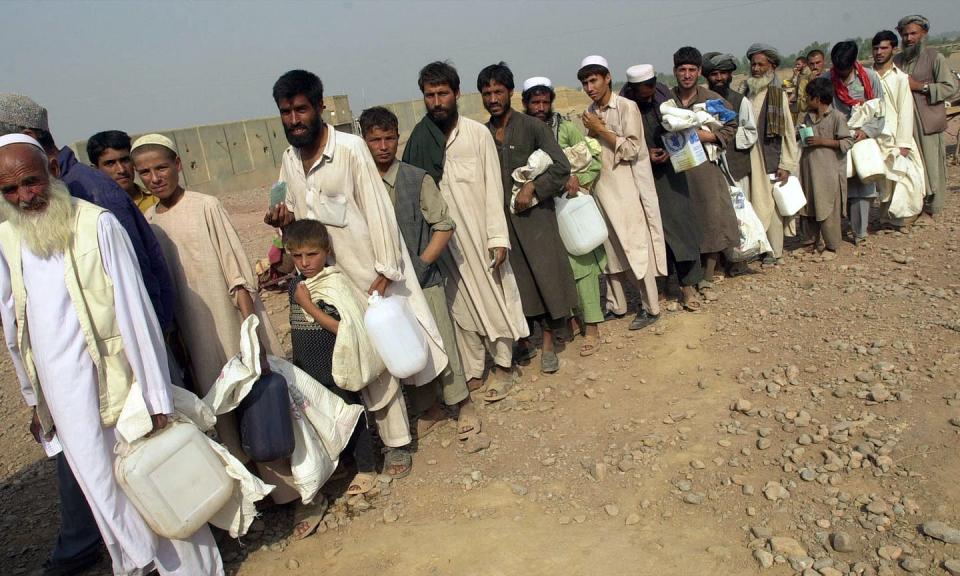 Afghans refugees line up for food disbursement at a camp in Pakistan in 2001.