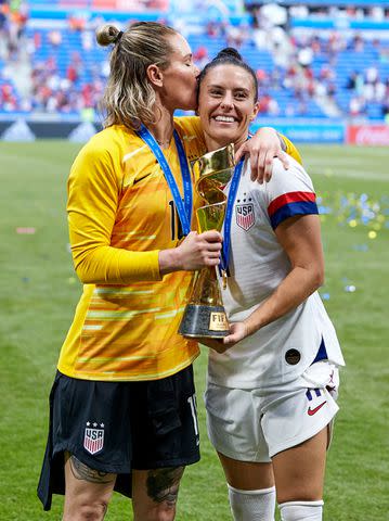<p>Quality Sport Images/Getty </p> Ali Krieger and Ashlyn Harris of the USA celebrate with the FIFA World Cup Trophy in 2019