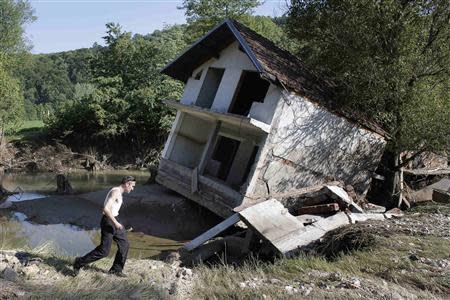 A man walks past a house tilted by floods in the town of Valjevo, southwest from Belgrade May 21, 2014. Picture taken May 21. REUTERS/Marko Djurica