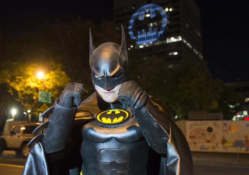 A man dressed in a Batman costume poses for a photo in front of the Batman signal projected onto a building to celebrate Batman Day in Montreal, Saturday, Sept. 21, 2019. The night sky all over the world is lighting up Saturday with an illumination of the famed bat insignia to mark a special anniversary for Batman. DC Comics is carrying off a celebration of Batman Day to mark the 80th anniversary of the appearance of crimefighter Bruce Wayne and his masked hidden identity. (Graham Hughes/The Canadian Press via AP)