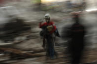 In this slow expose photograph, members of rescue services work in the debris of a collapsed building, in Izmir, Turkey, Monday, Nov. 2, 2020. In scenes that captured Turkey's emotional roller-coaster after a deadly earthquake, rescue workers dug two girls out alive Monday from the rubble of collapsed apartment buildings three days after the region was jolted by quake that killed scores of people. Close to a thousand people were injured. (AP Photo/Emrah Gurel)