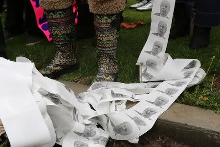 A protester holds toilet paper bearing pictures of U.S. President Donald Trump as people denounce policies of the president on President's Day at the Not My President's Day Rally in Los Angeles, California February 20, 2017. REUTERS/David McNew