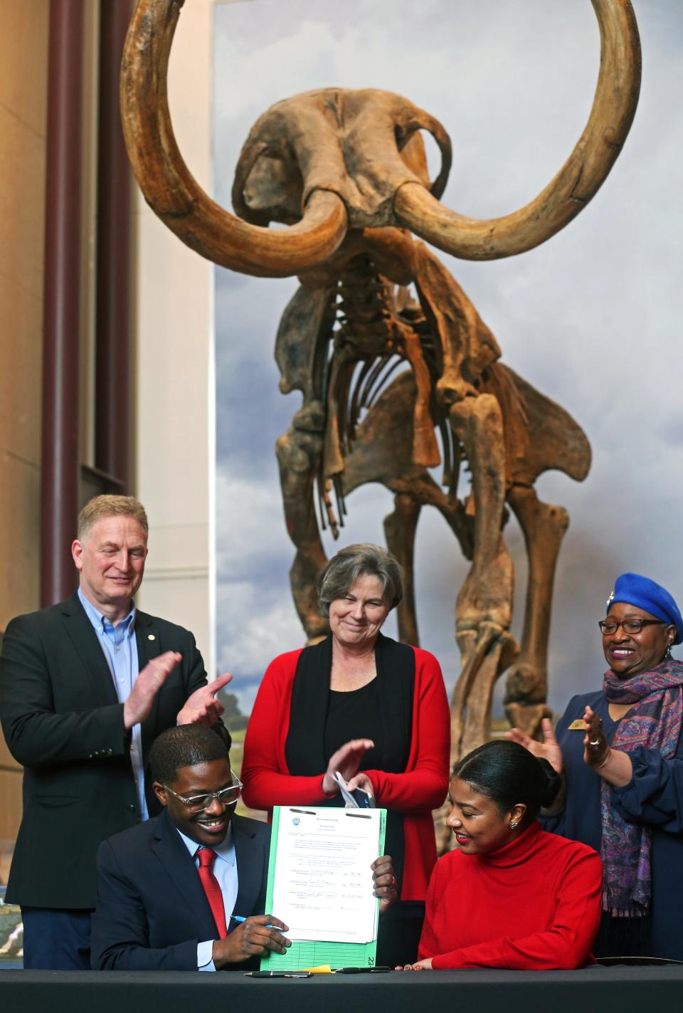 Milwaukee County Executive David Crowley, left seated and County Board Chairwoman Marcelia Nicholson, right seated, show legislation that was sign that will provide $45 million in funding for construction of the Milwaukee Public Museum’s new museum building on Monday, March 21 2022.