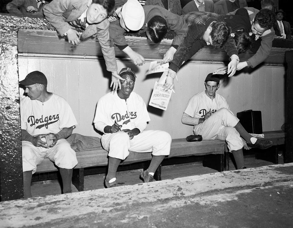 original caption 4111947 new york, ny youthful brooklyn dodger's rooters and fans, reach over from behind the dugout at ebbets field today, trying to get an autograph from jackie robinson, the first negro ever to reach the major league, joined the brooklyn team, yesterday he came from the montreal team, the dodgers played an exhibition game against the new york yankees today