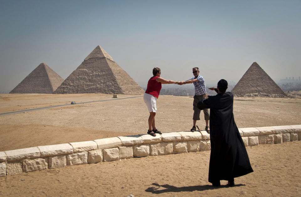 FILE - In this Thursday, Sept. 27, 2012 file photo, foreign tourists visit the historical site of the Giza Pyramids, near Cairo, Egypt. The past month saw a drop in tourists to Egypt, scared off by scenes of protests and clashes over the constitution, in new pain to a crucial industry gutted the past two years by turmoil. Tourism workers worry things won’t get any better even now that the charter has been passed: Egypt’s power struggles threaten to erupt into more unrest at any time, and some fear Islamists will eventually try to rein in alcohol and beach tourism. (AP Photo/Khalil Hamra, File)