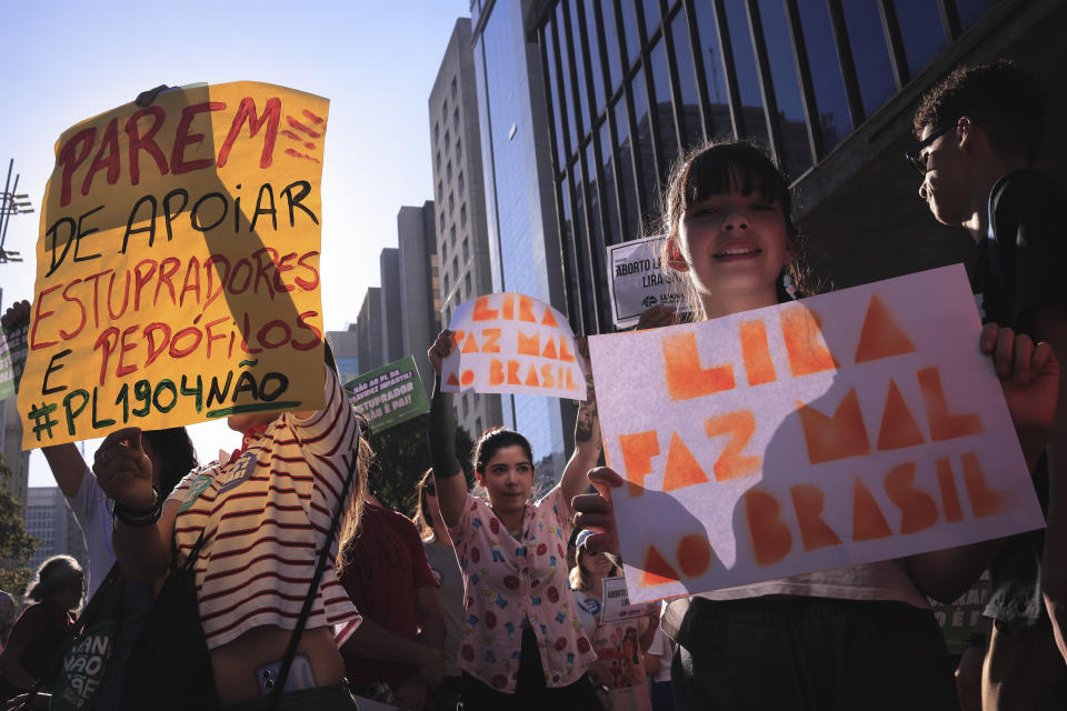 Abortion rights activists marching against an anti-abortion congressional bill, hold signs with messages that read in Portuguese: "Stop supporting rapists and pedophiles", left, and "Lira is bad for Brazil", in reference to the leader of Brazil's lower house of Congress, along Paulista Avenue in Sao Paulo, Saturday, June 15, 2024. (AP Photo/Ettore Chiereguini)