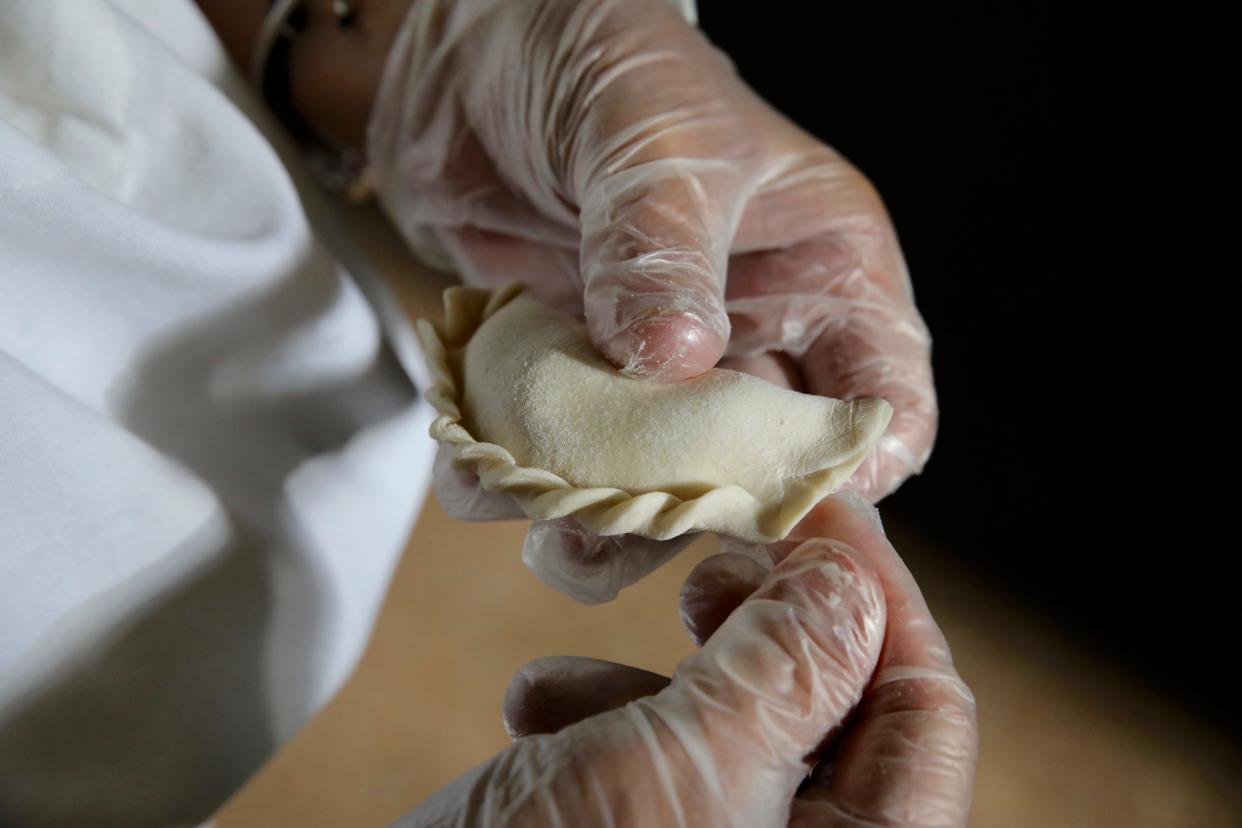 A volunteer demonstrates how pierogis are pinched and sealed by hand Monday, July 18, 2022, in the old St. Stanislaus School in Rockford