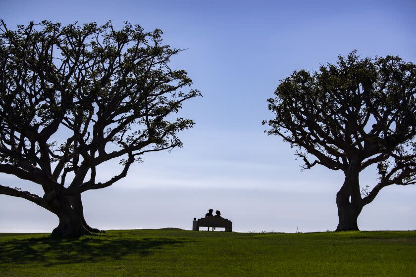 MALIBU, CA - October 16, 2022 - A couple enjoy balmy weather along with an ocean view from a bench on the lawn at Alumni Park at Pepperdine University in Sunday, Oct. 16, 2022 in Malibu, CA. (Brian van der Brug / Los Angeles Times)