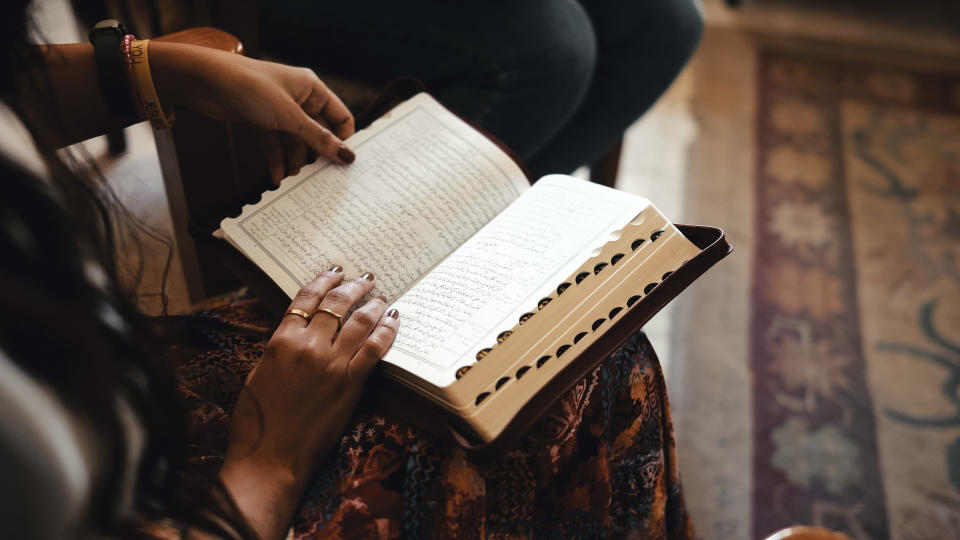 A book on a lap with hands on the pages