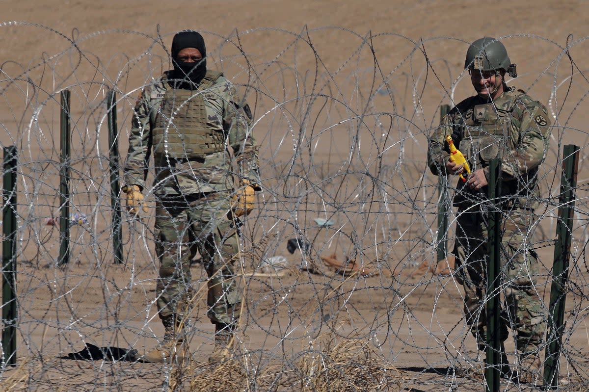 A Texas National Guard agent near a barbed wire fence installed to prevent the entry of migrants across the Rio Bravo/Grande from Ciudad Juarez (AFP via Getty Images)