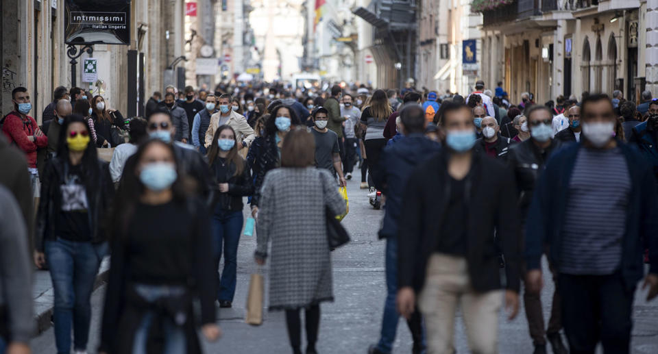 People wearing masks walk down a busy street in Italy. Source: AAP