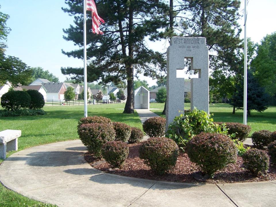 In this photo, a circa 1959 memorial to the original St. Antoine Church and Cemetery is viewed in the foreground, and the “new” memorial, dedicated in 2000, is visible in the background.  The burial ground was abandoned in 1830, and the church was razed in 1842 and property sold to Israel Ilgenfritz of the Ilgenfritz Nursery Company.