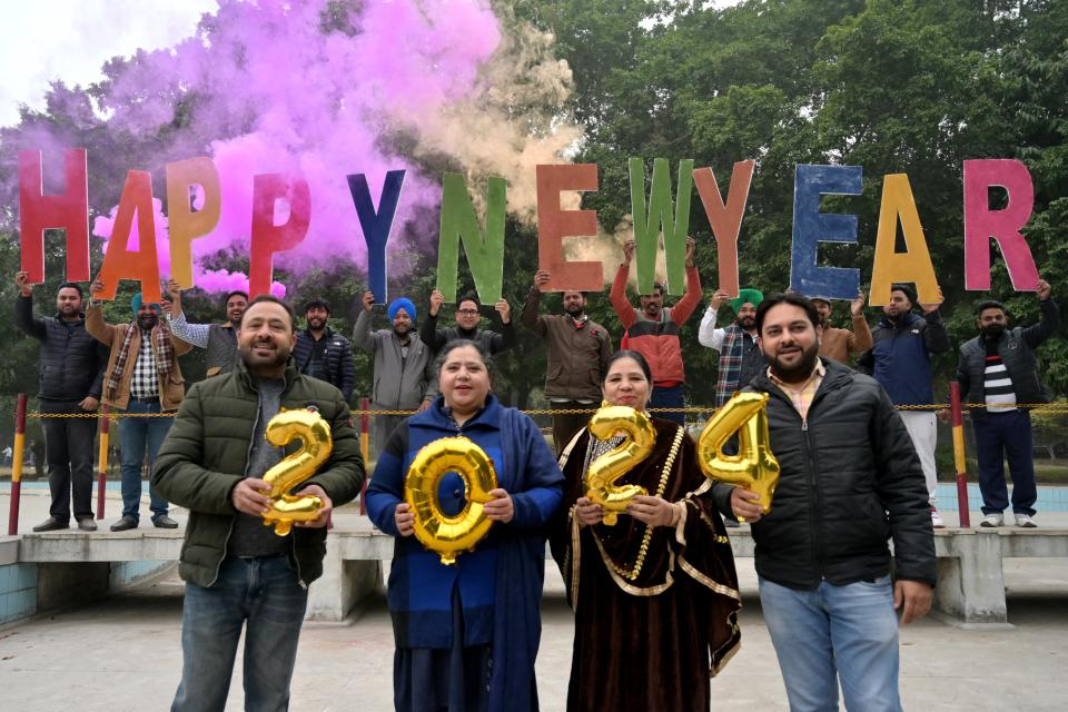 People holding 'Happy New Year' letters cutout pose for photos during New Year's Eve celebrations in Amritsar (AFP via Getty Images)