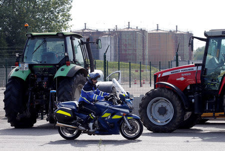 A gendarme rides his motobike past tractors parked by French farmers, members of the FNSEA, the country's largest farmers' union, to block the access of a petrol depot in Reichstett near Strasbourg, France, June 11, 2018. REUTERS/Vincent Kessler