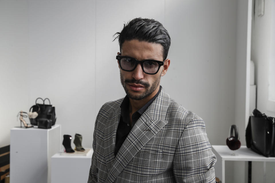 Fashion designer Karim Daoudi poses in front of his creations, in Milan, Italy, Sunday, Sept. 27, 2020. (AP Photo/Luca Bruno).