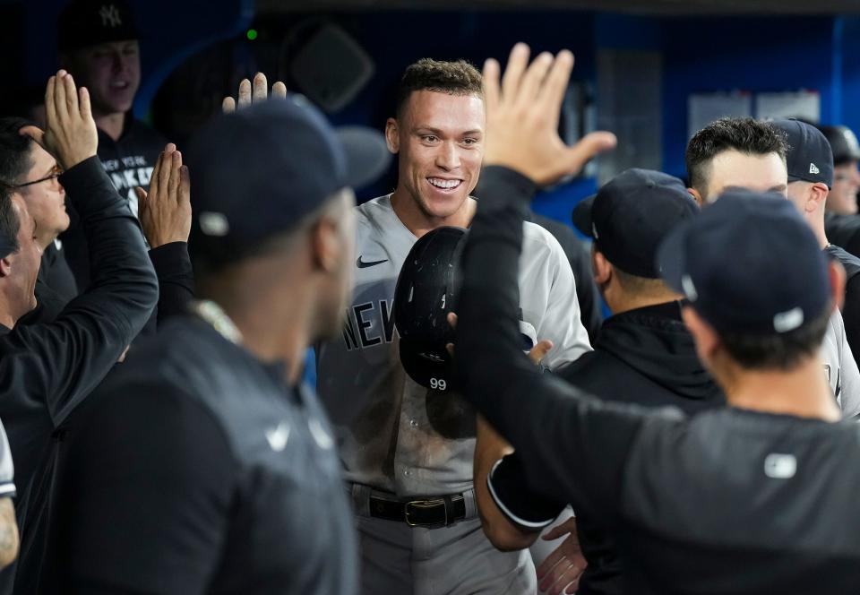 New York Yankees' Aaron Judge is congratulated in the dugout after his 61st home run of the season, a two-run shot, against the Toronto Blue Jays during the seventh inning of a baseball game Wednesday, Sept. 28, 2022, in Toronto.