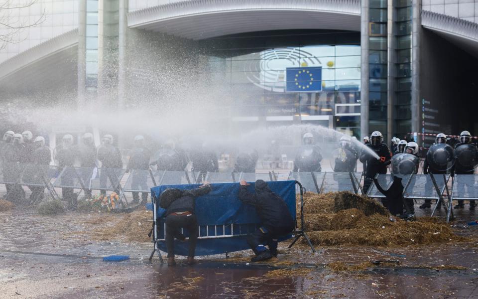 Anti-riot police use water to disperse people during a protest by farmers outside the European Parliament