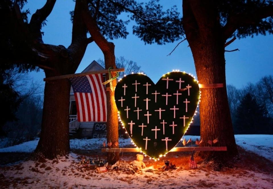 In this Dec. 14, 2013, file photo, a makeshift memorial with crosses for the victims of the Sandy Hook Elementary School shooting massacre stands outside a home in Newtown, Conn., on the one-year anniversary of the shootings.