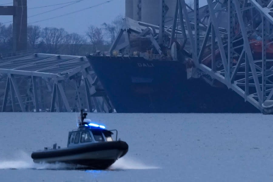 A container ship rests against wreckage of the Francis Scott Key Bridge as night falls on Tuesday, March 26, 2024, as seen from Sparrows Point, Md. The ship rammed into the major bridge in Baltimore early Tuesday, causing it to collapse in a matter of seconds and creating a terrifying scene as several vehicles plunged into the chilly river below. (AP Photo/Matt Rourke)