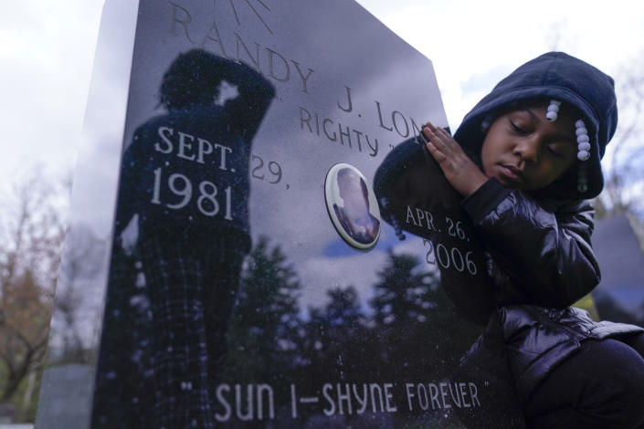 Xia’la Long looks at the tombstone of her uncle, Randy Long, who was murdered in 2006, while posing for a photo at a cemetery in Poughkeepsie, N.Y., April 19, 2023. An AP examination of data from 23 states shows that Black people are disproportionately denied aid from programs that reimburse victims of violent crime. (AP Photo/Seth Wenig)