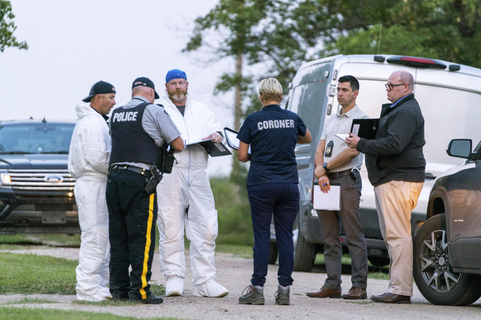 Investigators gather in front of the scene of a stabbing in Weldon, Saskatchewan, Sunday, Sept. 4, 2022. A series of stabbings at an Indigenous community and at another in the village of Weldon left multiple people dead and others wounded, Canadian police said Sunday as they searched for two suspects. (Heywood Yu/The Canadian Press via AP)