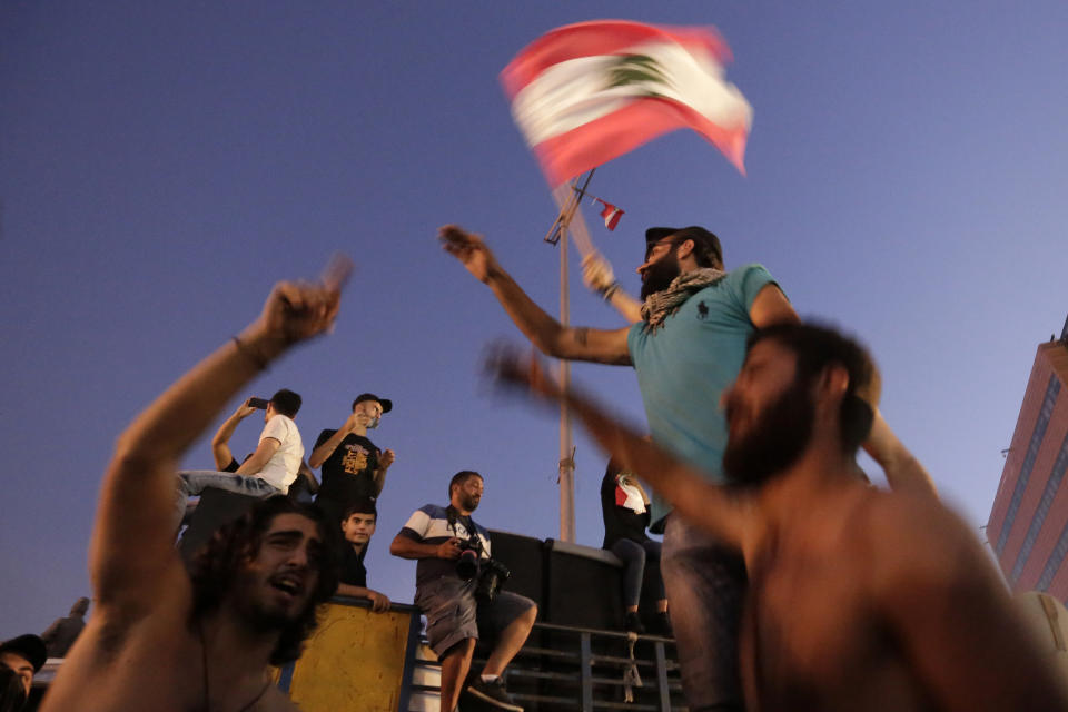 Anti-government protesters wave a Lebanese flag and shout slogans against the Lebanese government during a protest in Beirut, Lebanon, Monday, Oct. 21, 2019. Lebanon's Cabinet approved Monday sweeping reforms that it hopes will appease thousands of people who have been protesting for five days, calling on Prime Minister Saad Hariri's government to resign. (AP Photo/Hassan Ammar)