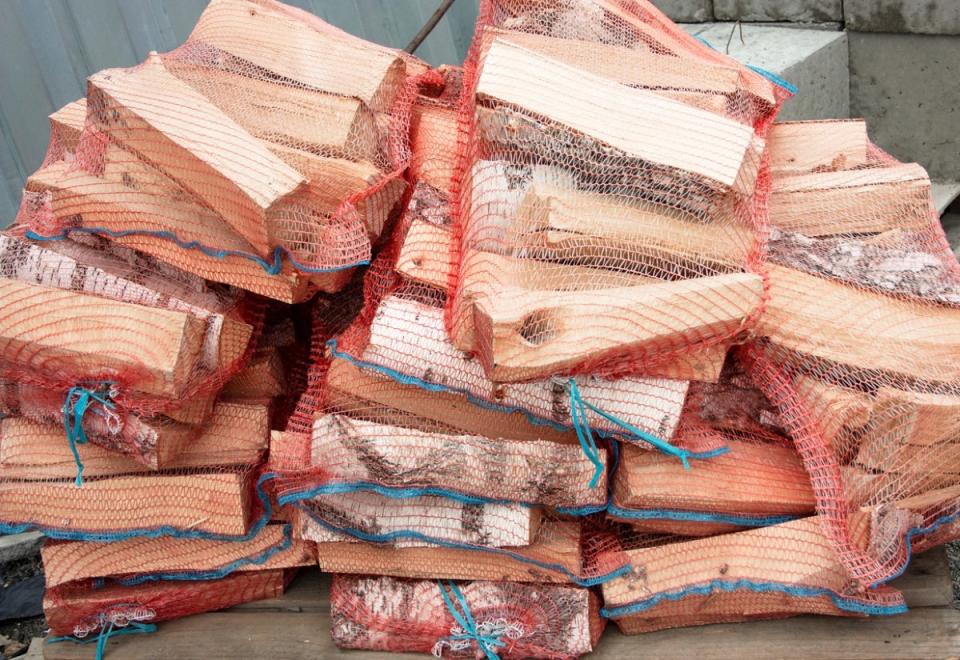 Stacks of firewood packaged in red mesh bags.
