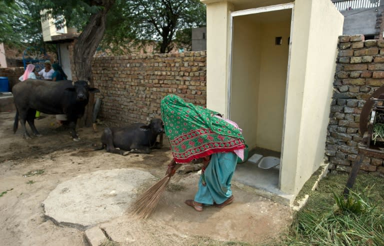 An Indian villager sweeps around a new toilet built as part of a public health drive launched by Prime Minister Narendra Modi