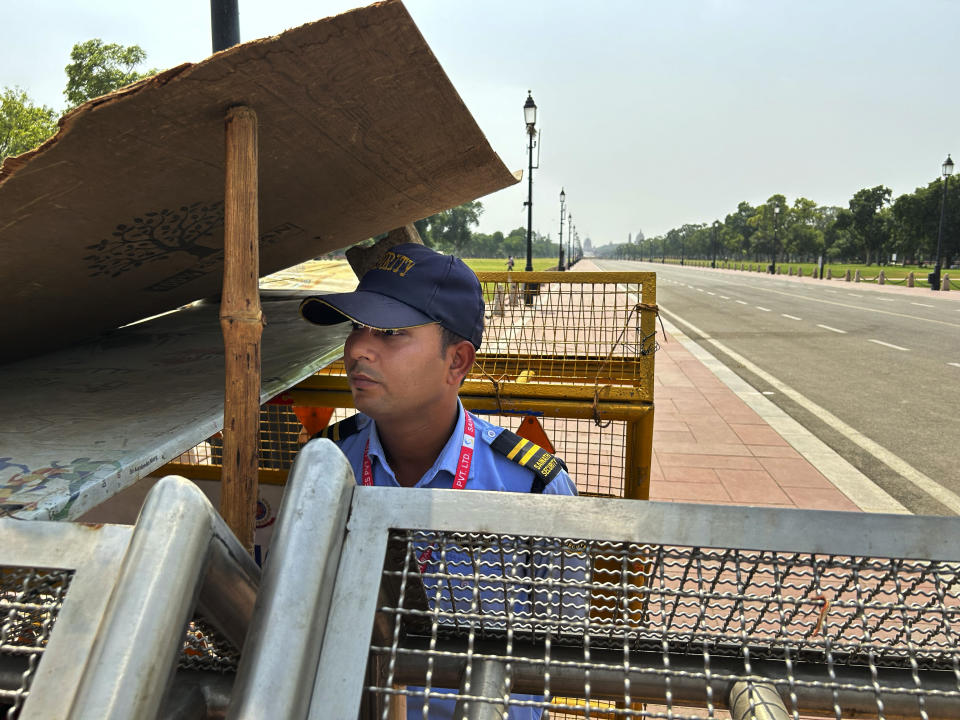 A private security guard stands under the shade of a used plyboard sheet propped up with the help of a stick in New Delhi, India, Saturday, May 18, 2024. Swathes of northwest India sweltered under scorching temperatures on Saturday, with the capital New Delhi under a severe weather alert as extreme temperatures strike parts of the country. (AP Photo/Shonal Ganguly)