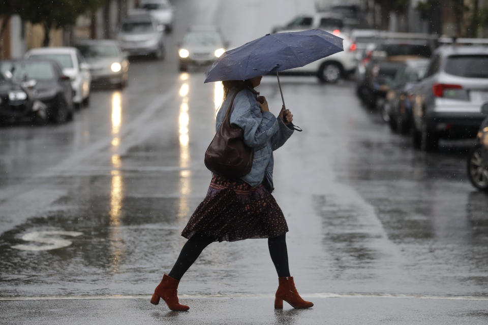 A woman carries an umbrella while walking in the rain in San Francisco, Tuesday, Nov. 26, 2019. Northern California and southern Oregon residents are bracing for a 'bomb cyclone' that's expected at one of the busiest travel times of the year. (AP Photo/Jeff Chiu)