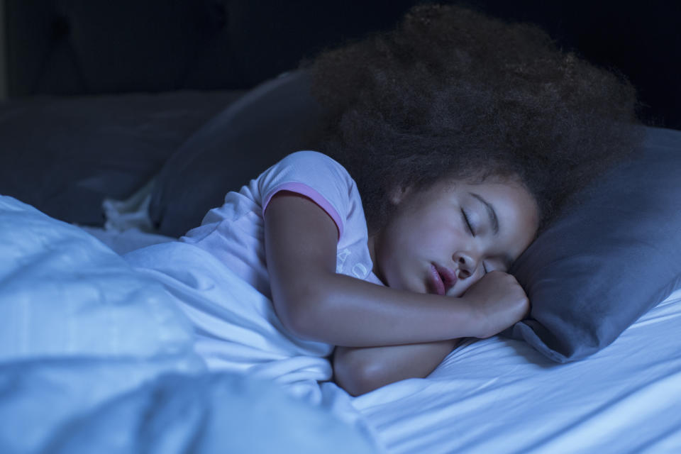 A child lies in bed sleeping at night. (Photo via Getty Images)