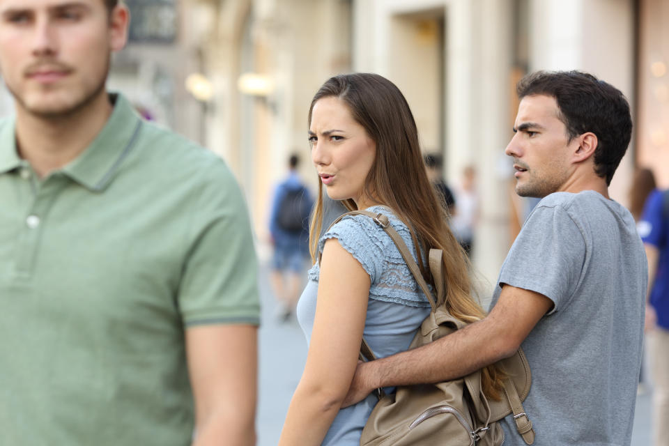 Disloyal woman looking at another man and her upset boyfriend.