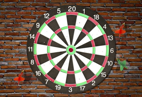 A dartboard with three darts that've completely missed the board.