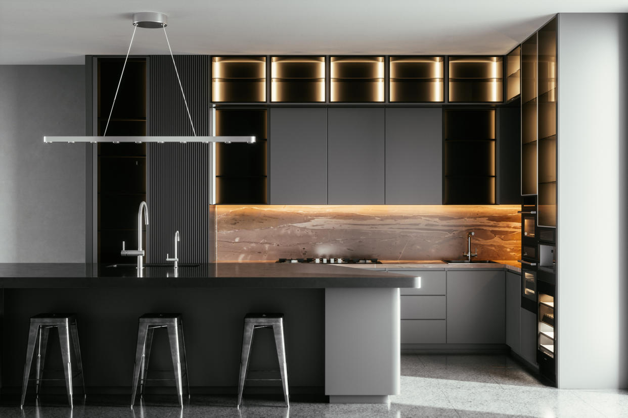  A black kitchen with lighting above the island. 