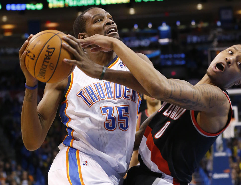 Kevin Durant, alero del Thunder de Oklahoma City, comete una falta sobre Damian Lillard, de los Trail Blazers de Portland, en el cuarto periodo del encuentro disputado el martes 21 de enero de 2014 (AP Foto/Sue Ogrocki)